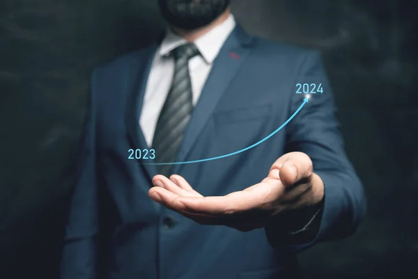 stock image The arrow rises from 2023 to 2024. A man holds in his hand