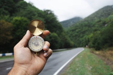 Bir elde pusula ve arka planda bir yol