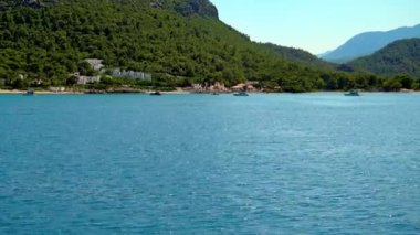 Ada boyunca yat, yat parkı, mavi göl, dağ manzarası, yeşil dağlar, mavi su, tekneler ve yatlar, eğlence yatları. Yüksek kalite 4k görüntü