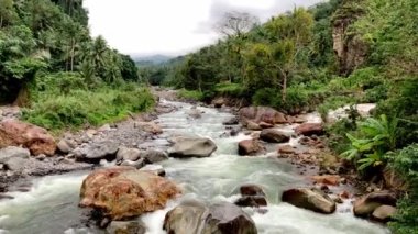Güçlü bir dağ nehri akıntısı kristal berraklığında ve buzlu su kayaların dibini kaplar. Yüksek kalite 4k görüntü