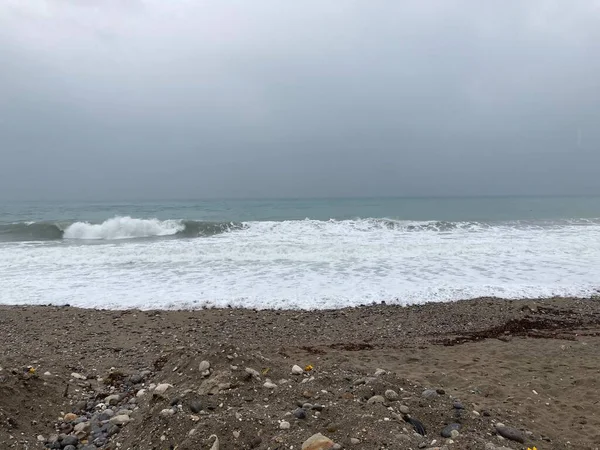 Çalkantılı deniz kum kıyısını çakıl taşlarıyla karıştırır. Yüksek kalite fotoğraf