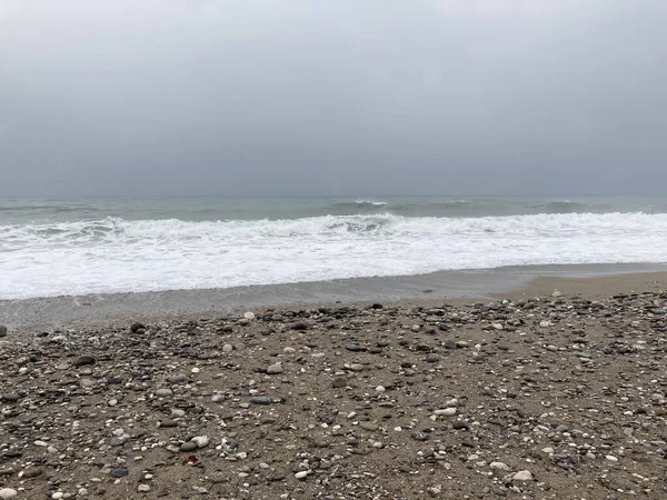 Çalkantılı deniz kum kıyısını çakıl taşlarıyla karıştırır. Yüksek kalite fotoğraf