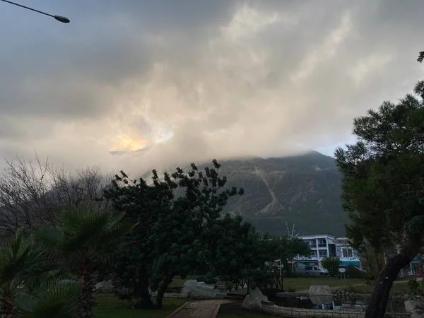 Düşük tüylü bulutlar yüksek dağların üzerinde asılı, tepelerini örtüyor. Yüksek kalite fotoğraf