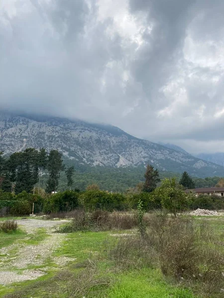 Düşük tüylü bulutlar yüksek dağların üzerinde asılı, tepelerini örtüyor. Yüksek kalite fotoğraf