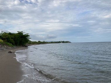 Denizin kumlu sahilinde küçük sıcak dalgalar yavaşça kıyıya vurur. Yüksek kalite fotoğraf