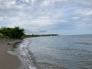 Denizin kumlu sahilinde küçük sıcak dalgalar yavaşça kıyıya vurur. Yüksek kalite fotoğraf
