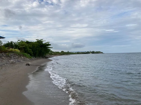 Denizin kumlu sahilinde küçük sıcak dalgalar yavaşça kıyıya vurur. Yüksek kalite fotoğraf
