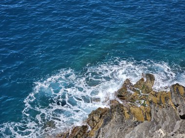 Okyanus dalgalarının yüksek açılı görüntüsü kayalara çarpıyor. Kopyalama alanı olan yatay fotoğraf. 