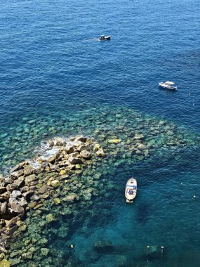 Manarola açıklarındaki Ligurian Denizi 'ndeki limanın dikey fotoğrafı. Yüzeyin altında küçük kayalar ve kayalar olan temiz suyun yüksek açılı görüntüsü. 