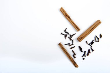 Beyaz yüzeyde karanfil ve tarçın çubukları var. Yüksek açı, fotokopi alanı solda. Yatay fotoğraf.