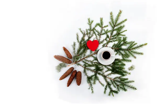 stock image Spruce branch with coffee in a cup on top. Red heart and spruce cones and a little lichen. Flatlay shot from high angle. Horizontal photo with copy space in the left part of image.