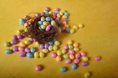 Sarı arka planda birden fazla renkli Paskalya yumurtası. Küçük kuş yuvasının üst açısı.