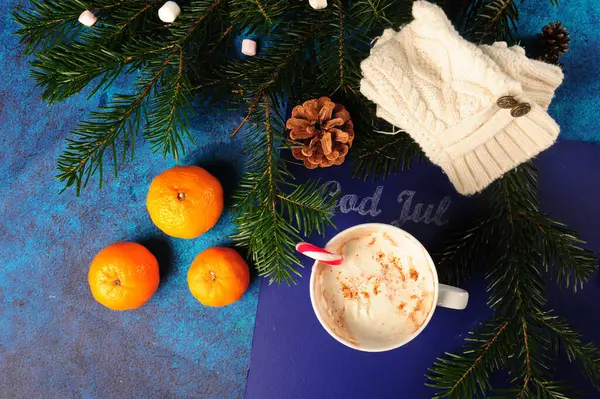 stock image Norwegian god jul Christmas greeting on blue blackboard partially covered in pine twigs. Cup of ot chocolate, cocoa with whipped cream and candy cane. Orangesand marshmallows.