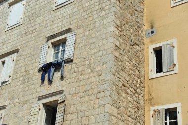 Budva, Karadağ 'daki eski tuğla bina. Kotlar güneşte kurumak için pencereden sarkıyor. Düşük açılı yatay fotoğraf.