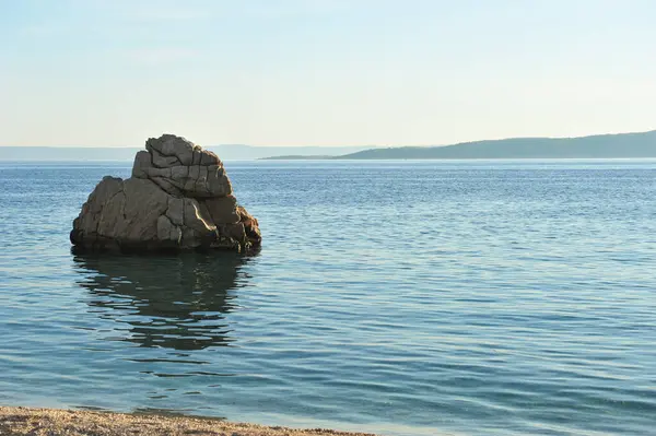 stock image large rock off the beach in Brela in Croatia. Copy space to the right.