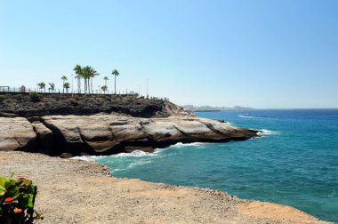 Playa de Los Americas, Tenerife, İspanya yakınlarındaki kayalıkların yakın görüntüsü. Mavi okyanus ve mavi gökyüzü.