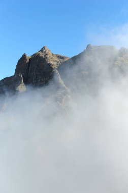 İspanya 'nın Tenerife adasındaki gizli dağ tepeleri. Masca Vadisi 'nin üzerindeki bulutlar. Dikey fotoğraf.