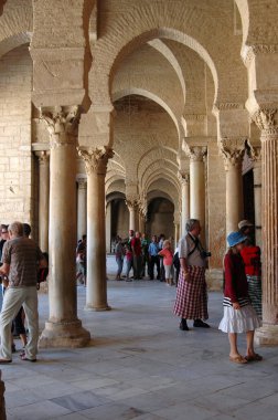 Tunus 'taki tapınağa giren turistlerin dikey fotoğrafı. İnsanlar dizlerini örtmek için bez giyiyorlar. Tunus.