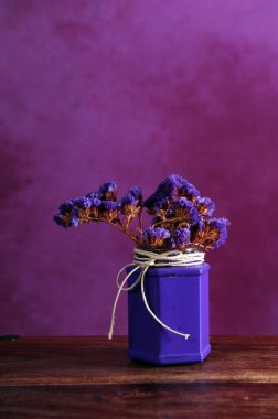 Mor boyalı cam ve doğal iple çizilmiş çiçek demetleri. Üst kısmında kopyalama alanı olan dikey fotoğraf.