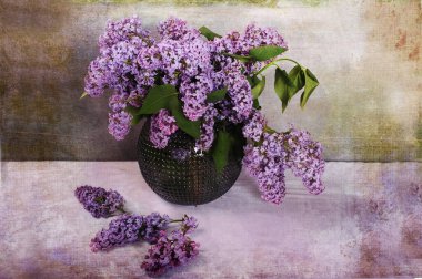 Yuvarlak vazoda mor leylakların sanatsal fotoğrafı. Masada birkaç leylak çiçeği yatıyor. Dijital desenli fotoğraf ve resim efekti.