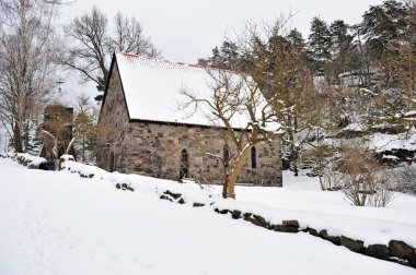 Loevoykapellet, Horten, Norveç 'te. Avrupa 'daki eski taştan kilisenin kış sahnesi. Kar örtülü yol. Resmin alt kısmında kopya alanı olan yatay fotoğraf.