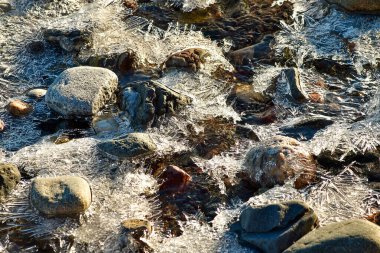 Sahilde buzla kaplı kayaların yatay fotoğrafı. Şubat 'ta güneşli bir gün.