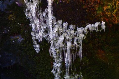 Taş duvardan sarkan buz saçaklarının güzel deseni. Kenarlarında kopya alanı olan sade tuşlu fotoğraf.
