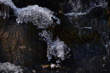 Güzel kış sanatı. Küçük şelalede buz kabarcıkları ve buz saçakları. Kopyalama alanı olan sade tuş fotoğrafı.