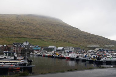 Sisli bir günde Faroe Adaları 'ndaki Sorvagur köyü. Baharda çimlerin altındaki liman ve binalar dağlarla kaplıydı..