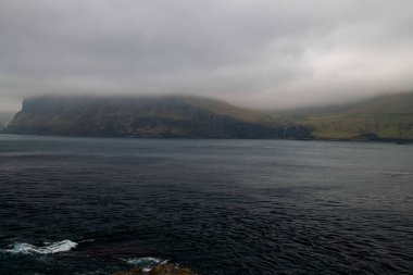 Faroe dağları ve kıyıları. Manzara için kasvetli bir hava. Şelaleler arka planda hafifçe görülebilir. Kopyalama alanı olan yatay fotoğraf.