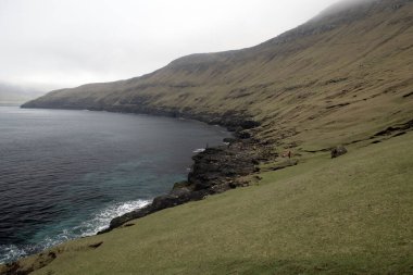 Faroe Adaları, Drangarnir 'den geri dönmek için bekleyen tanınmayan turistler. Sisli bir dfay üzerinde dramatik Faroe deniz manzarası.