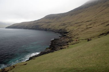 Faroe Adaları, Drangarnir 'den geri dönmek için bekleyen tanınmayan turistler. Sisli bir dfay üzerinde dramatik Faroe deniz manzarası.