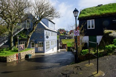 Güneşli bir bahar gününde Torshavn, Faroe Adaları 'ndaki dükkanlar ve eski geleneksel Faroe binalarıyla sokak manzarası.