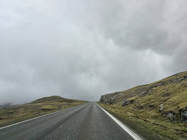 Faroe Adaları 'ndaki dağların üzerinde yoğun sis var. Kötü havada araba yolculuğu..