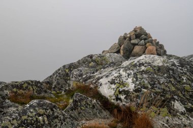 Dağın tepesindeki güzel renklerde Cairn işaretleri sisli gökyüzü ve arka planda uzanıyor. Kopyalama alanı olan yatay fotoğraf.