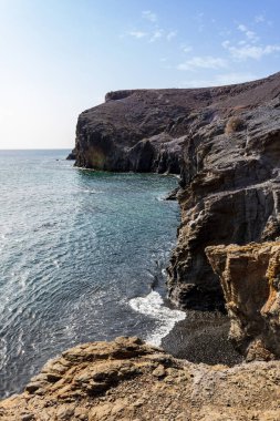 Playa Mujeres, Lanzarote, Kanarya Adaları, İspanya yakınlarında güneşli bir günde mavi gökyüzü olan Rocky sahili..