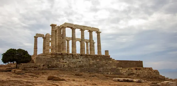 stock image Majestic Ruins of the Ancient Temple of Poseidon at Cape Sounion Under Cloudy Skies Overlooking the Aegean Sea. High-quality photo