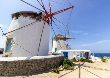 Mikonos adasında bulutlu gökyüzünün altında geleneksel Yunan yel değirmenleri. Yunanistan 'ın Cyclades kentindeki ikonik Mykonos yel değirmenlerinin hava görüntüsü. Seyahat ve mimari konsepti. Yüksek kalite fotoğraf