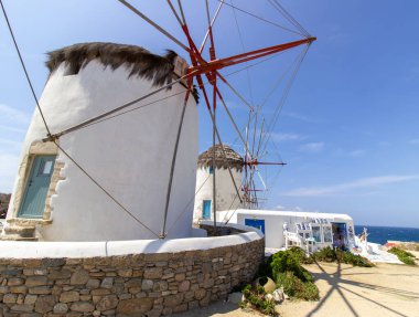 Mikonos adasında bulutlu gökyüzünün altında geleneksel Yunan yel değirmenleri. Yunanistan 'ın Cyclades kentindeki ikonik Mykonos yel değirmenlerinin hava görüntüsü. Seyahat ve mimari konsepti. Yüksek kalite fotoğraf