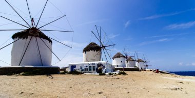 Traditional Greek windmills on Mykonos island under cloudy sky. Aerial view of iconic Mykonos windmills in Cyclades, Greece. Travel and architecture concept. High quality photo clipart