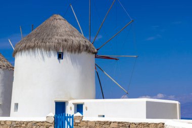 Mikonos adasında bulutlu gökyüzünün altında geleneksel Yunan yel değirmenleri. Yunanistan 'ın Cyclades kentindeki ikonik Mykonos yel değirmenlerinin hava görüntüsü. Seyahat ve mimari konsepti. Yüksek kalite fotoğraf