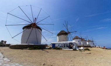 Traditional Greek windmills on Mykonos island under cloudy sky. Aerial view of iconic Mykonos windmills in Cyclades, Greece. Travel and architecture concept. High quality photo clipart