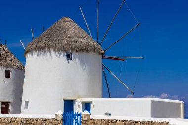 Mikonos adasında bulutlu gökyüzünün altında geleneksel Yunan yel değirmenleri. Yunanistan 'ın Cyclades kentindeki ikonik Mykonos yel değirmenlerinin hava görüntüsü. Seyahat ve mimari konsepti. Yüksek kalite fotoğraf