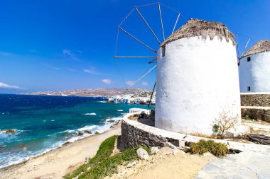 Mikonos adasında bulutlu gökyüzünün altında geleneksel Yunan yel değirmenleri. Yunanistan 'ın Cyclades kentindeki ikonik Mykonos yel değirmenlerinin hava görüntüsü. Seyahat ve mimari konsepti. Yüksek kalite fotoğraf