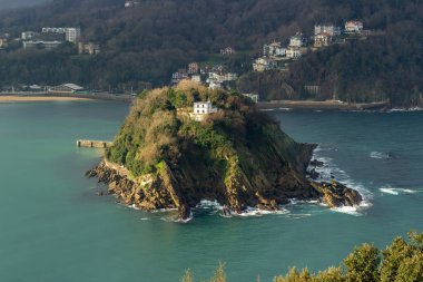 Santa Clara Adası, arka planda yemyeşil ve kıyı binaları olan turkuaz sularla çevrili, San Sebastian, İspanya. - Evet. Yüksek kalite fotoğraf