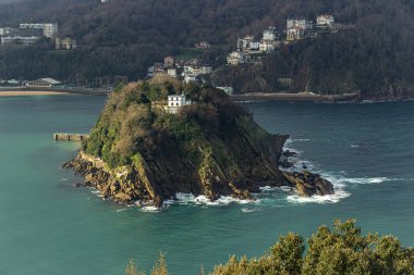 Santa Clara Adası, arka planda yemyeşil ve kıyı binaları olan turkuaz sularla çevrili, San Sebastian, İspanya. - Evet. Yüksek kalite fotoğraf