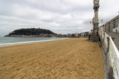 San Sebastian, İspanya 'da gün batımında kıyıya yakın binaları ve arka planında tepeleri olan kumsal. Kıyı kenti ve doğal manzara. Yüksek kalite fotoğraf