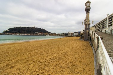 San Sebastian, İspanya 'da gün batımında kıyıya yakın binaları ve arka planında tepeleri olan kumsal. Kıyı kenti ve doğal manzara. Yüksek kalite fotoğraf