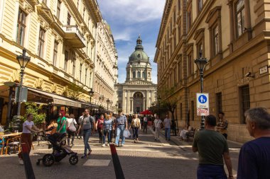 Macaristan 'ın başkenti Budapeşte' de mavi gökyüzü altında ziyaretçiler tarafından çevrelenmiş büyük kubbesi ve ikiz çan kuleleriyle Aziz Stephens Bazilikası. 
