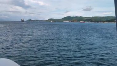Bir gemiden alınan görüntüler. Birkaç gemi, ada ve bulutlu bir gökyüzü görebilirsiniz.